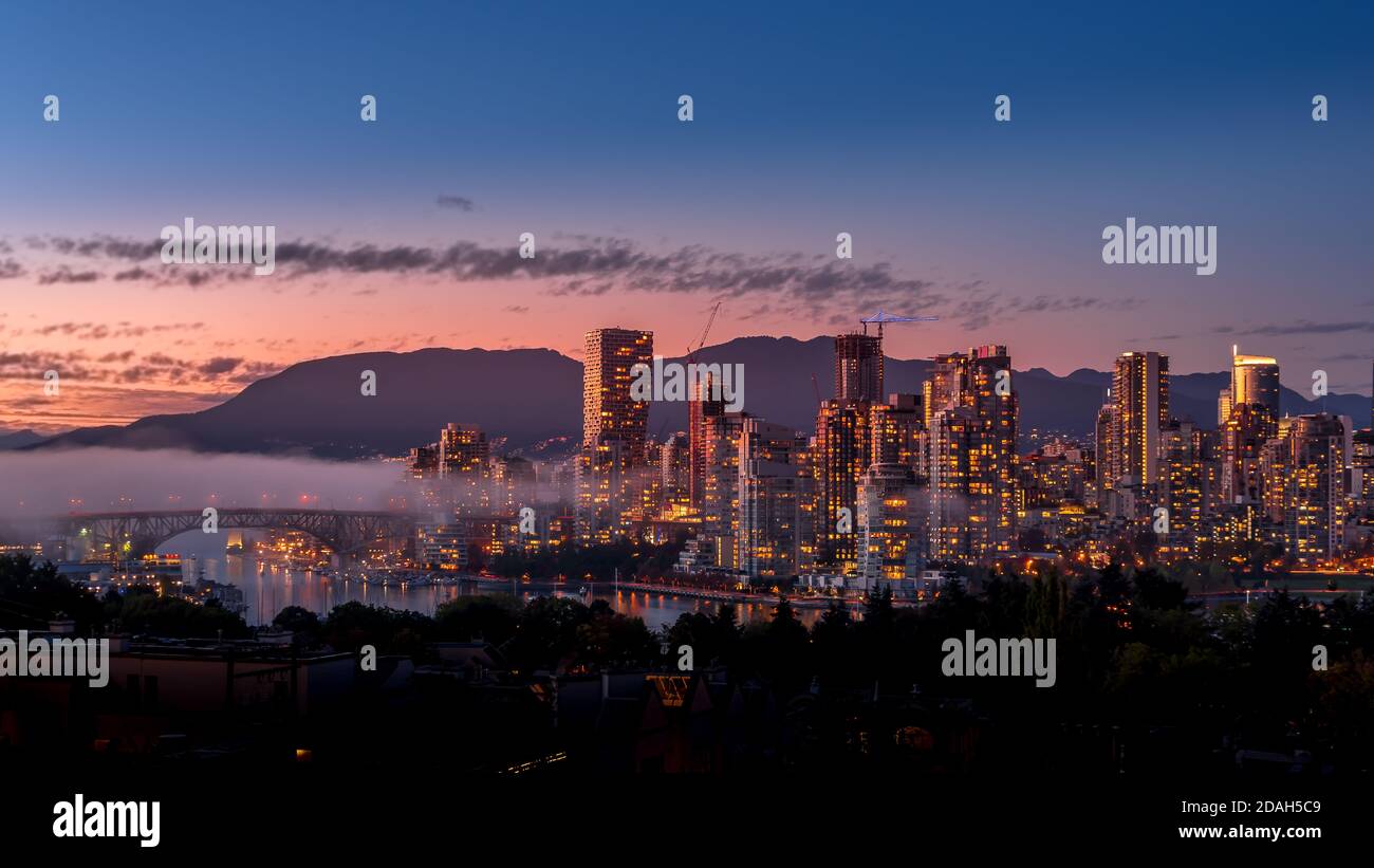 Le brouillard survolant le pont Granville alors que le soleil se couche au-dessus de la ligne d'horizon du centre-ville de Vancouver, en Colombie-Britannique, au Canada. Vue depuis la rive sud o Banque D'Images