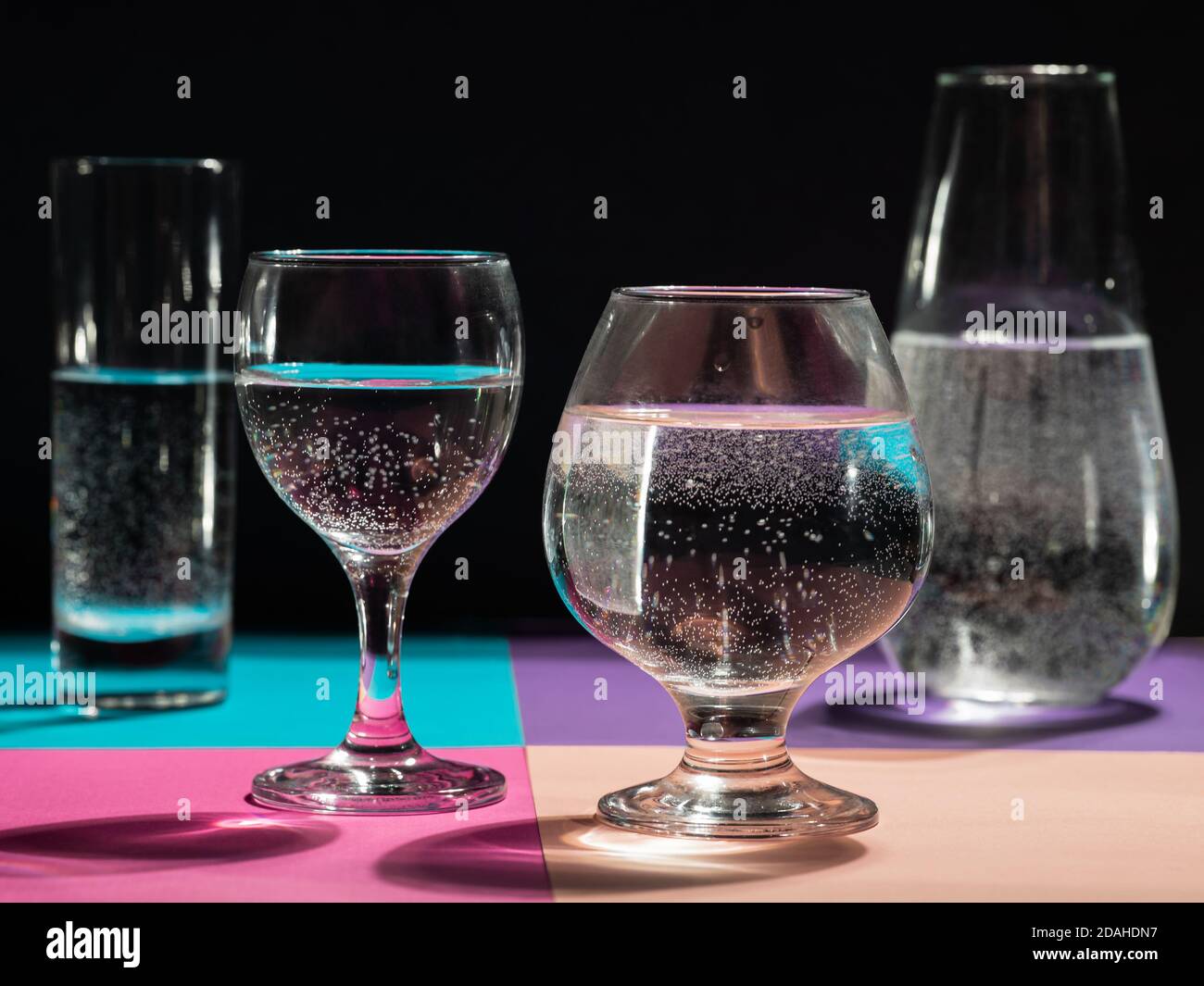 quatre verres d'eau différents se tiennent sur du papier multicolore Banque D'Images