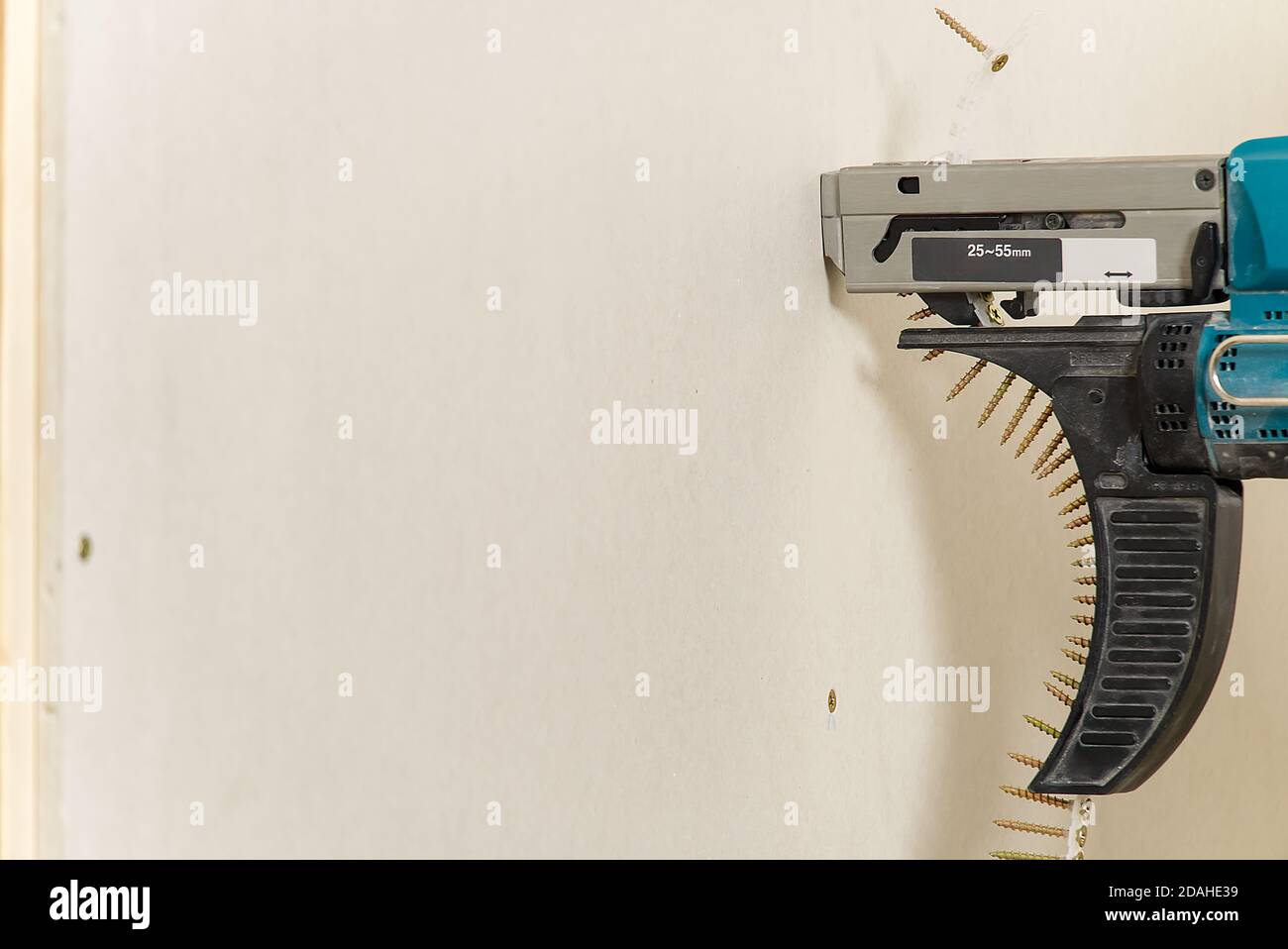Réparation de chambre. Bâtiment. L'employé fixe la cloison sèche à l'aide d'un tournevis. Fixation de la cloison sèche au cadre en bois avec un pistolet à vis à tête bombée. Banque D'Images