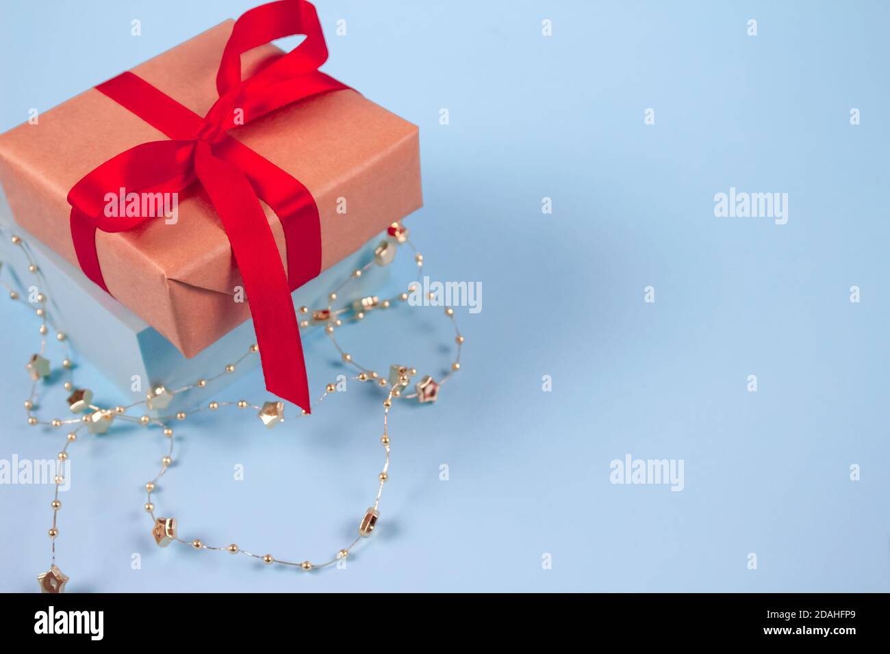 Boîte cadeau ornée d'un noeud rouge sur un fond bleu festif avec des sparkles dorés et un espace de rédaction pour votre texte. Noël, nouvel an, Saint Valentin ou Banque D'Images