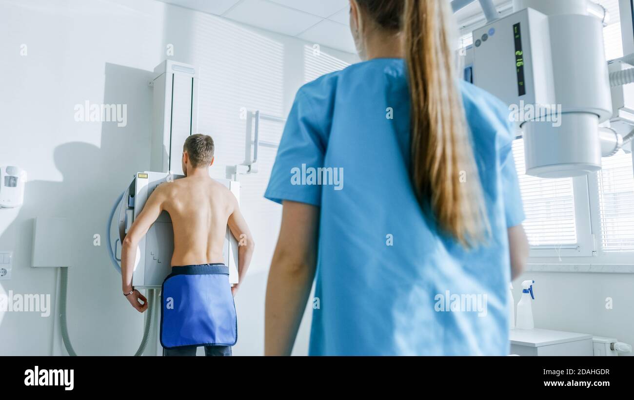À l'hôpital, un homme debout face au mur pendant que le technicien médical le regarde avant de passer une radiographie. Acquisition pour les fractures, cassées Banque D'Images