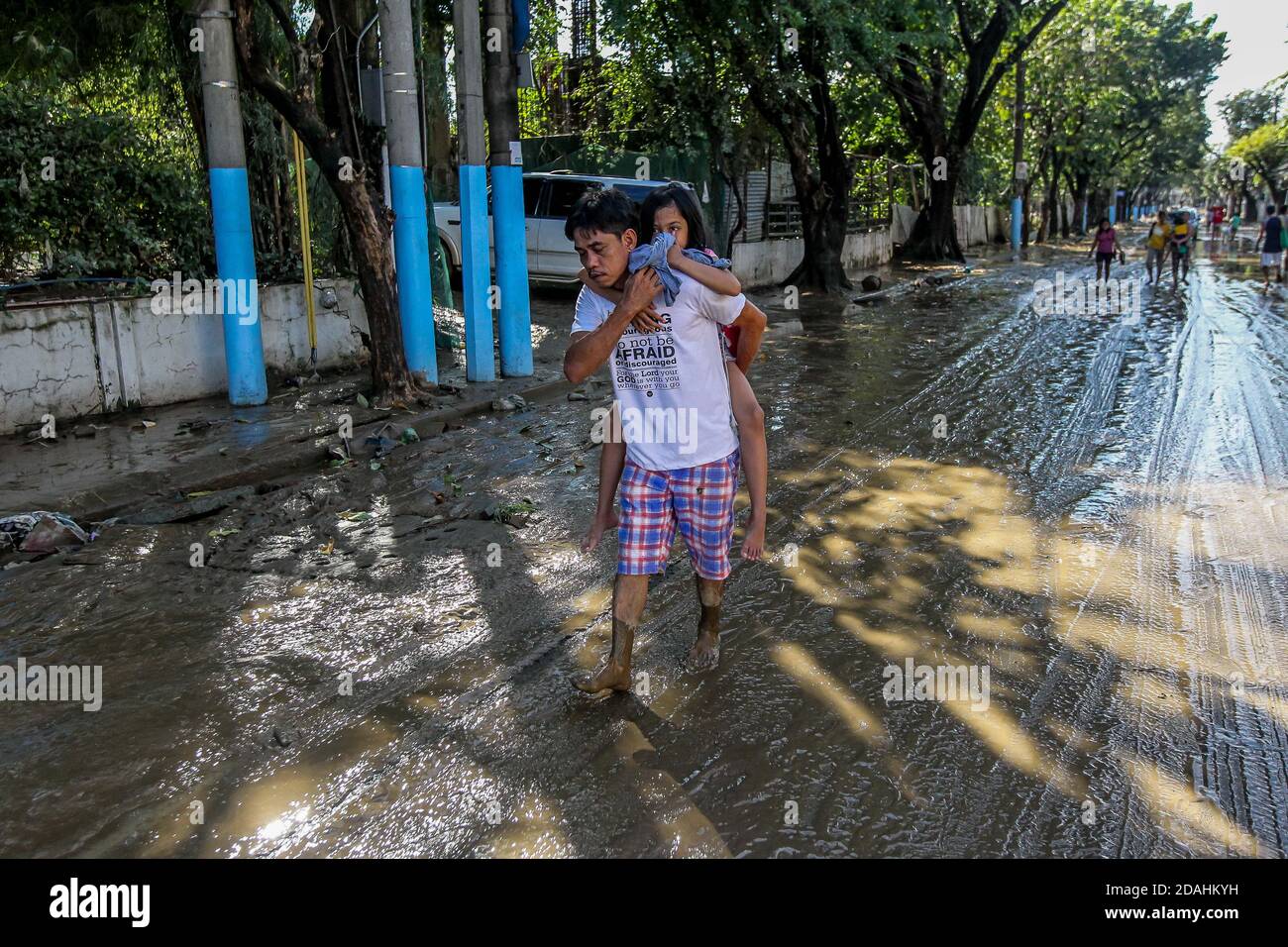 Manille, Philippines. 13 novembre 2020. Un homme porte sa fille alors qu'il marche sur une route boueuse après l'inondation provoquée par le typhon Vamco à Manille, aux Philippines, le 13 novembre 2020. Le gouvernement philippin a déclaré vendredi que le typhon Vamco, qui a causé des inondations et des glissements de terrain dévastateurs dans l'île principale de Luzon, avait tué au moins 14 personnes, a déclaré les responsables. Crédit: Rouelle Umali/Xinhua/Alamy Live News Banque D'Images