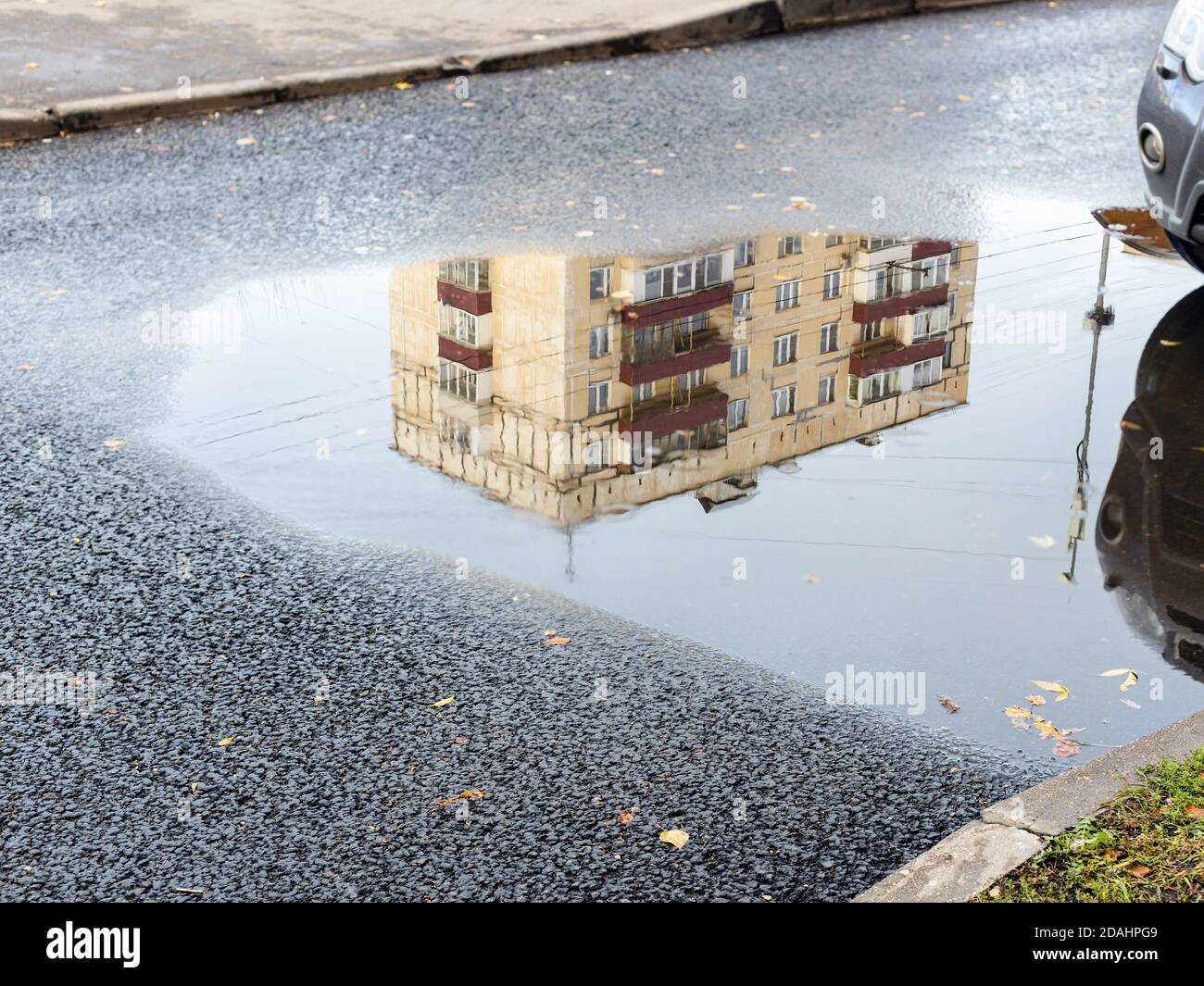 flaque de pluie avec reflet de la maison urbaine municipale sur l'asphalte route en ville le jour de l'automne Banque D'Images