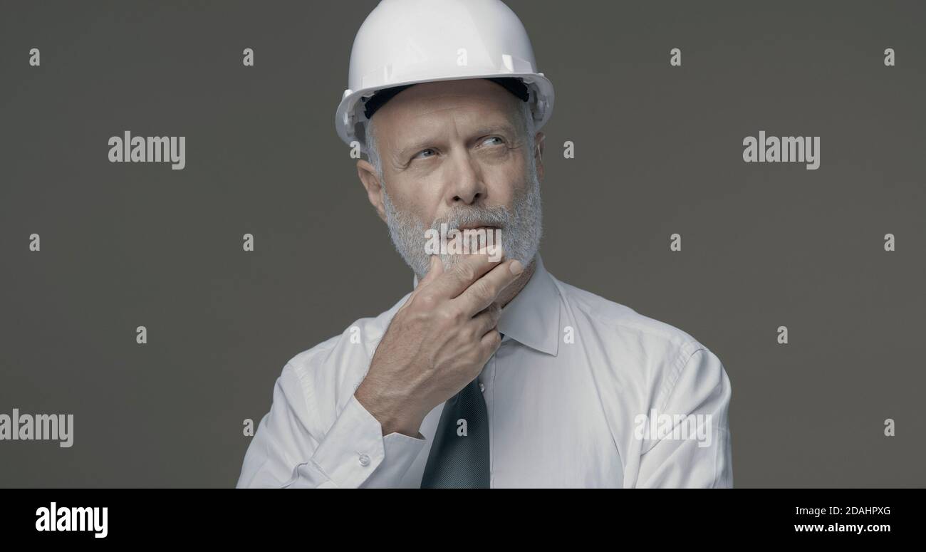 Homme d'affaires expérimenté et ingénieur confiant pensant main sur le menton Banque D'Images Homme d'affaires expérimenté et ingénieur confiant pensant main sur le menton Banque D'Images