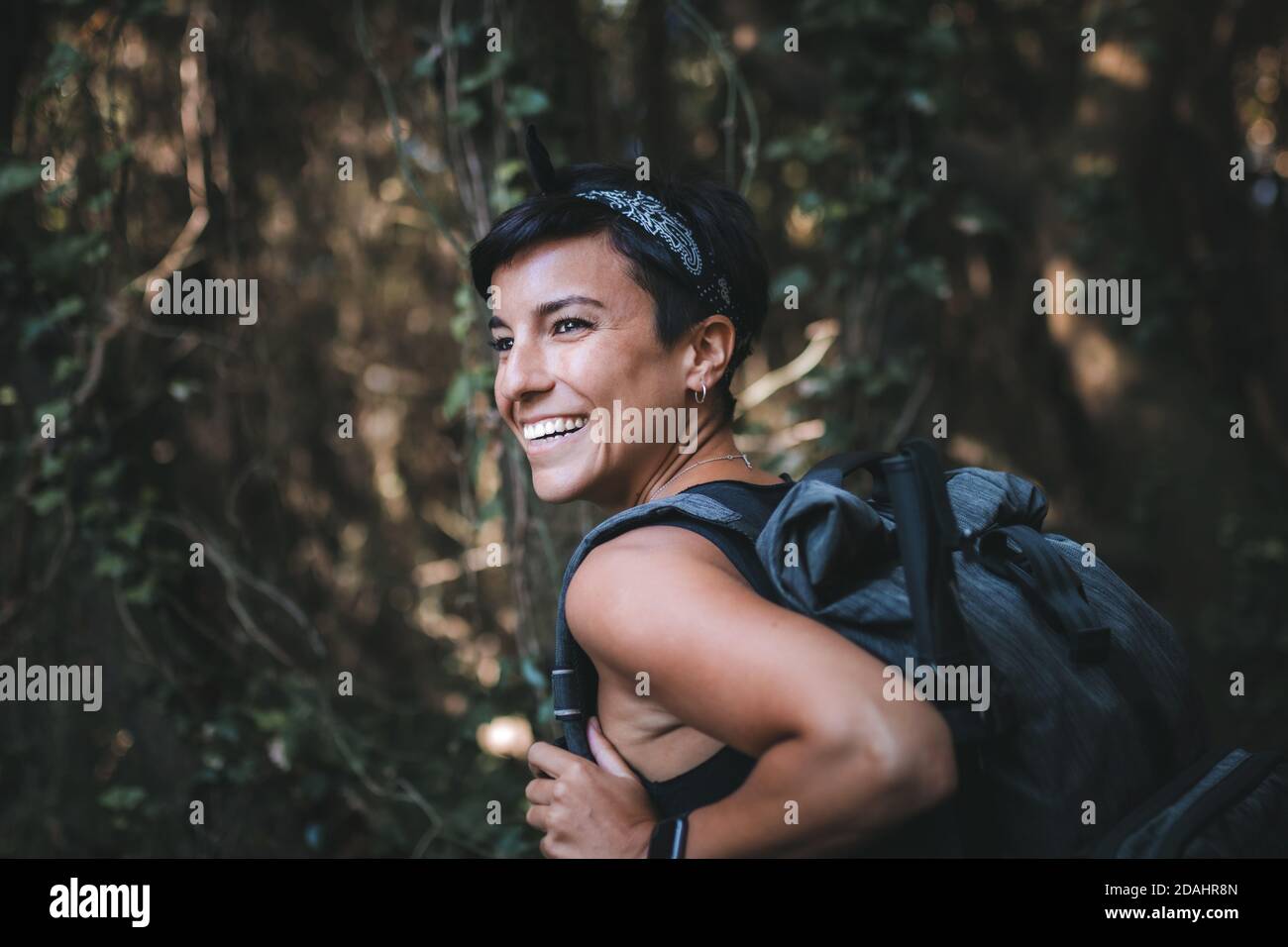 Portrait d'une belle femme joyeuse souriant admirant la nature dans la  forêt tout en randonnée avec un sac à dos Photo Stock - Alamy