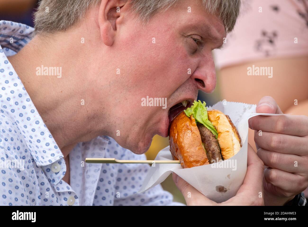 Un homme affamé mangeant un hamburger délicieux Banque D'Images