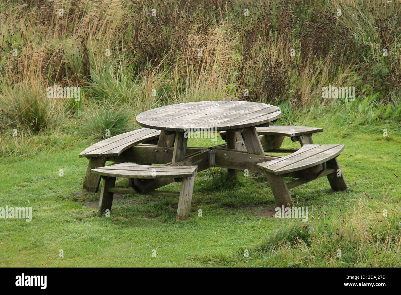 Une table de pique-nique extérieure ronde en bois avec sièges. Banque D'Images