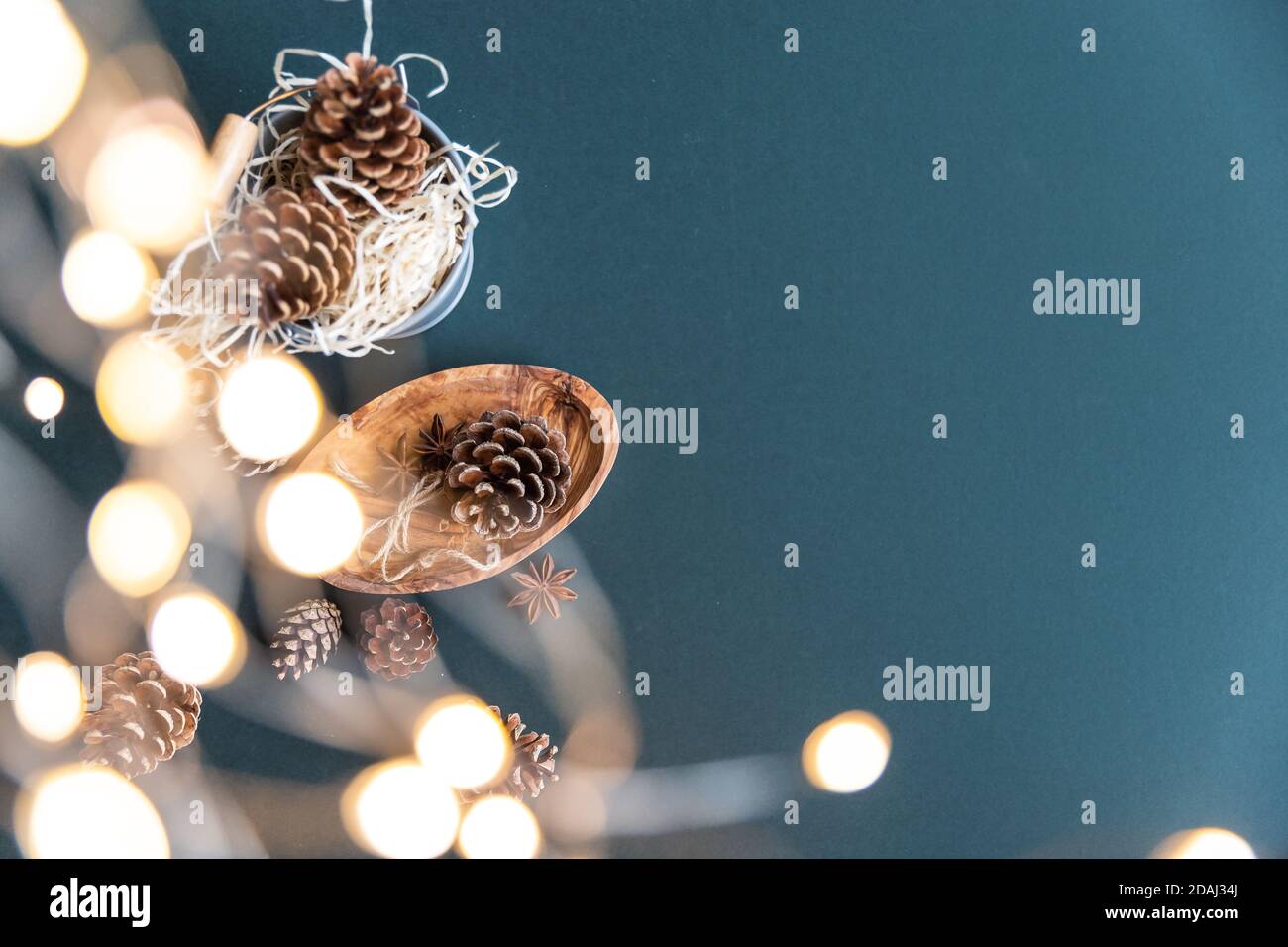 Décoration de Noël alternative ou décoration écologique zéro déchet, cônes de pin et lumières de Noël sur un fond sarcelle Banque D'Images