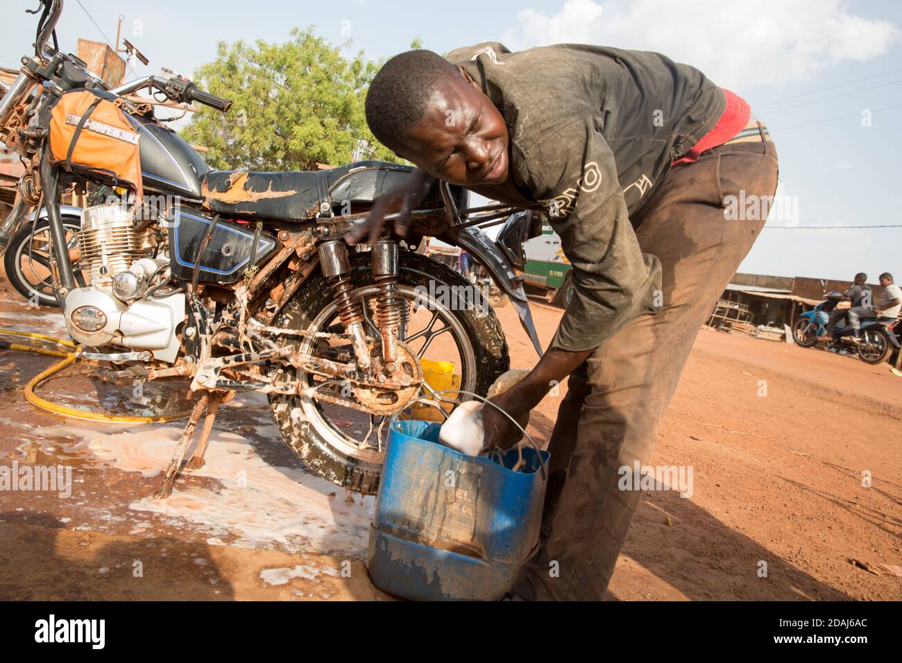 Selingue, Mali, le 25 avril 2015; Tiema Tounkara, 14 ans, et Afon Troure, 19 ans, qui nettoient les motos, travaillent tous deux pour leur père. Tiema va à l'école, et travaille dans l'après-midi. Afon a quitté l'école l'année dernière. Ils facturent 250 CFA pour nettoyer chaque vélo, et nettoyer environ 15 vélos chaque jour entre eux. Banque D'Images