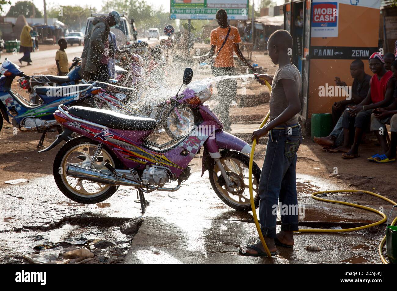 Selingue, Mali, le 25 avril 2015; Tiema Tounkara, 14 ans, et Afon Troure, 19 ans, qui nettoient les motos, travaillent tous deux pour leur père. Tiema va à l'école, et travaille dans l'après-midi. Afon a quitté l'école l'année dernière. Ils facturent 250 CFA pour nettoyer chaque vélo, et nettoyer environ 15 vélos chaque jour entre eux. Banque D'Images