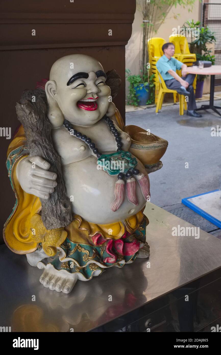 La petite statue d'un « Bouddha riant » ou Budai / Hotei, dans un restaurant chinois à Geylang, Singapour Banque D'Images