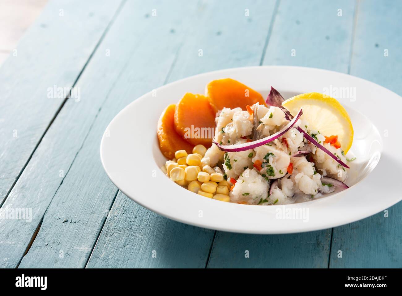 Ceviche péruvienne traditionnelle avec poisson, patate douce, maïs et légumes sur table en bois bleu Banque D'Images