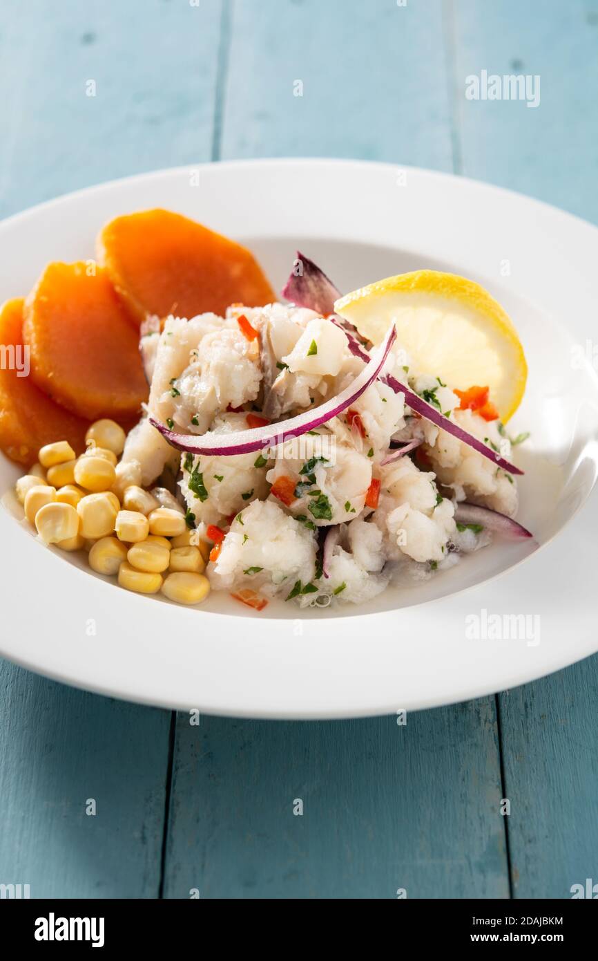 Ceviche péruvienne traditionnelle avec poisson, patate douce, maïs et légumes sur table en bois bleu Banque D'Images