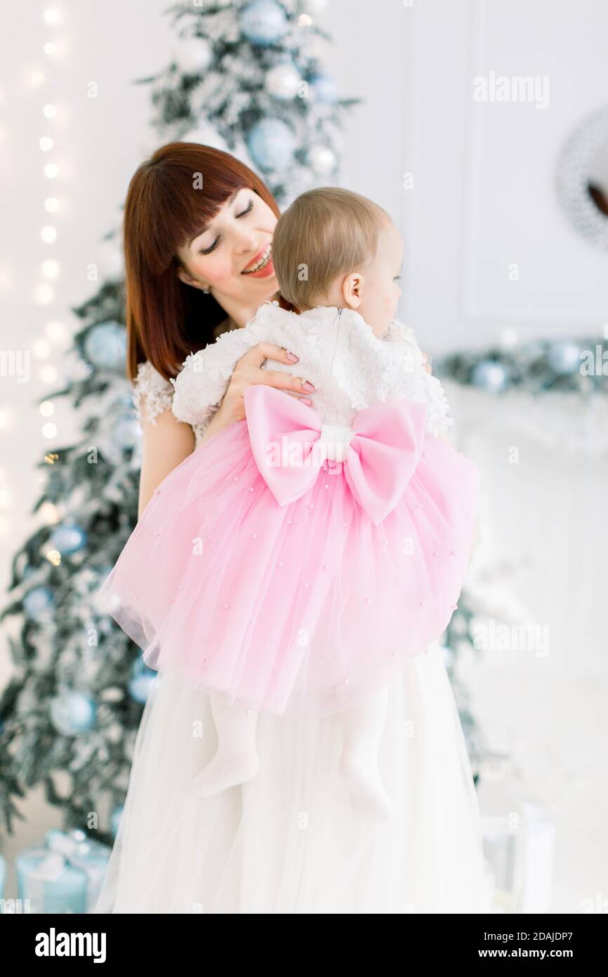 Petite fille portant une belle robe rose et blanche avec un gros noeud sur le dos appreciant le temps avec sa belle momie souriante dans une piece claire decoree Photo Stock