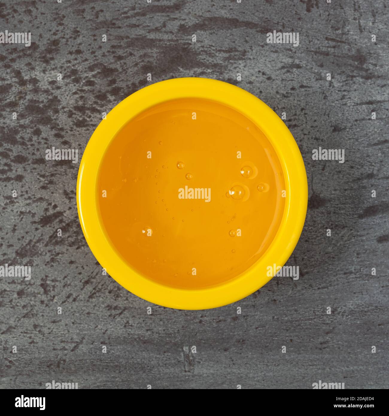 Bol jaune de sirop de maïs léger sur fond gris éclairé par un éclairage naturel. Banque D'Images