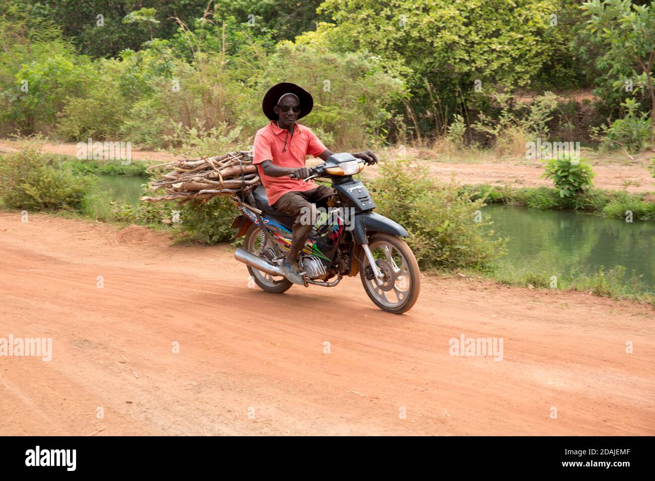 Selingue, Mali, 26 avril 2015; UN agriculteur conduit à vélo à travers la canelle principale d'irrigation. Banque D'Images