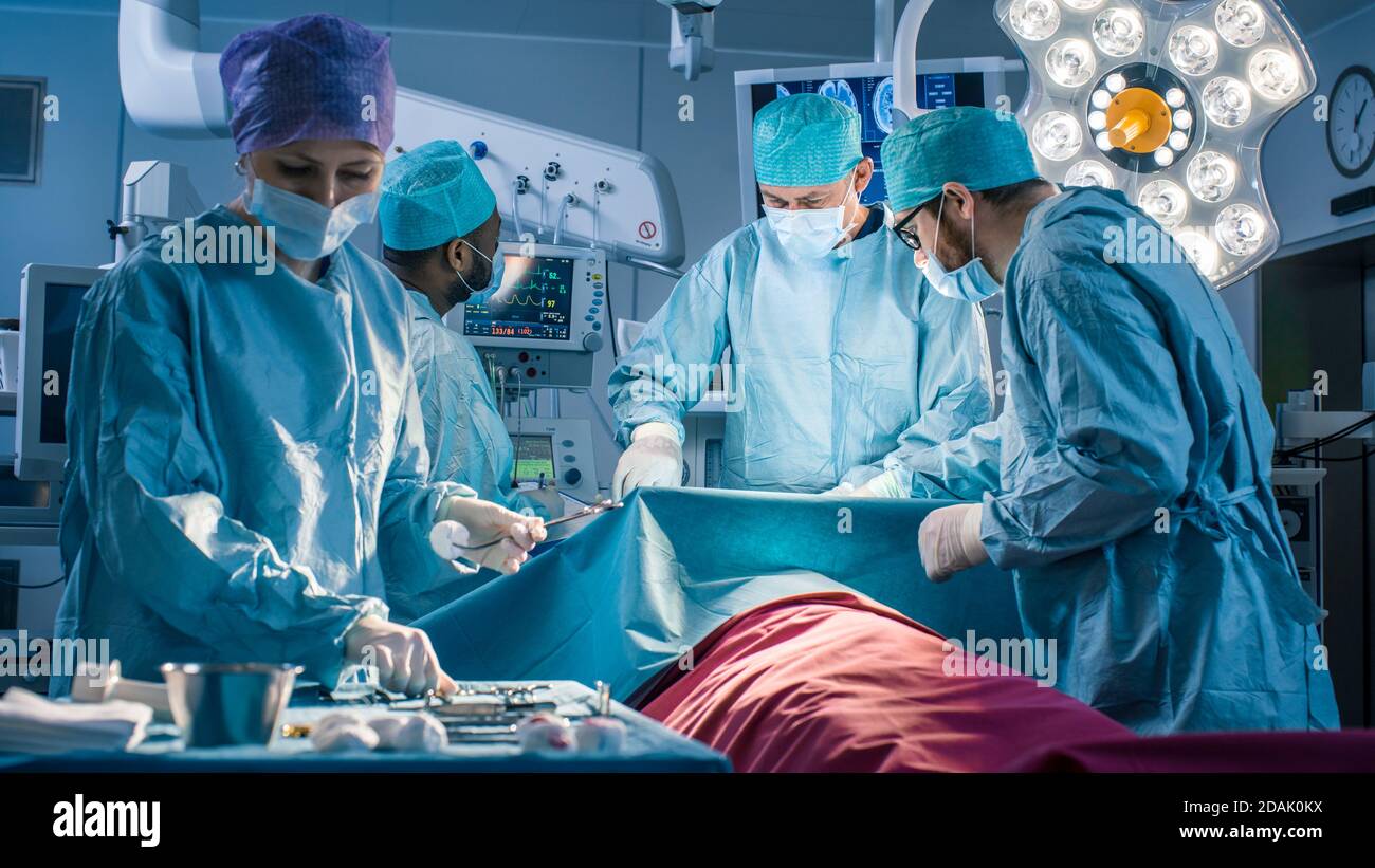 Équipe diversifiée de chirurgiens professionnels effectuant une chirurgie invasive sur un patient dans la salle d'opération de l'hôpital. L'infirmière choisit les instruments Banque D'Images