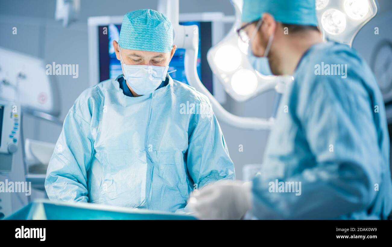 Tourné dans la salle d'opération, l'assistant remet les instruments aux chirurgiens pendant le fonctionnement. Les chirurgiens effectuent l'opération. Médecins professionnels Banque D'Images