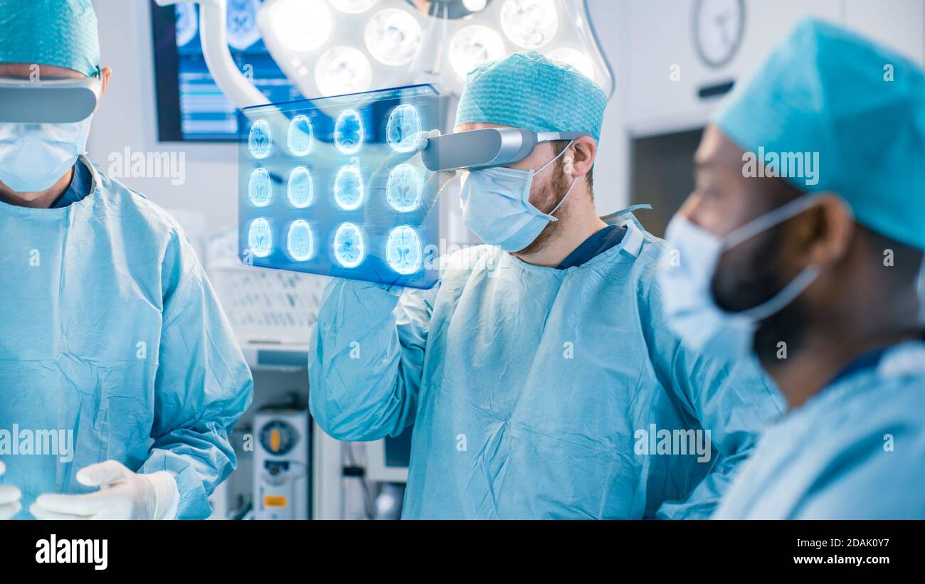Les chirurgiens portant des lunettes de réalité augmentée effectuent la chirurgie de réalité augmentée de l'état de l'art dans l'hôpital de haute technologie. Le chirurgien regarde les acquisitions du cerveau et Banque D'Images