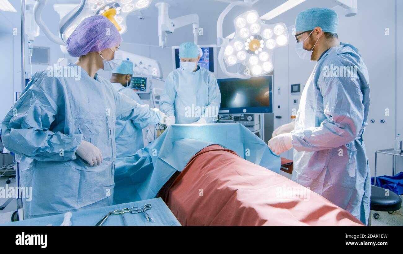 Équipe diversifiée de chirurgiens professionnels effectuant une chirurgie invasive sur un patient dans la salle d'opération de l'hôpital. L'infirmière transmet l'instrument à un chef Banque D'Images