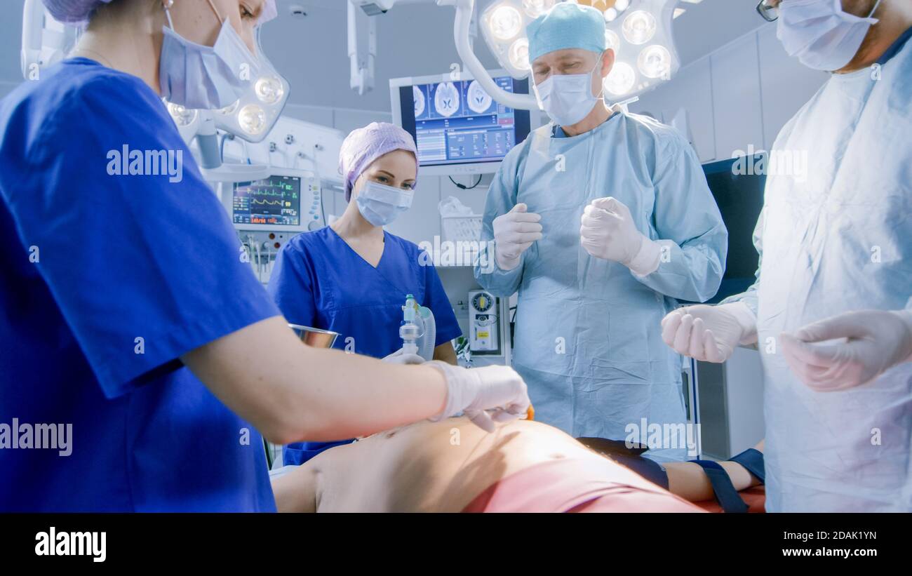 Dans la salle d'opération de l'hôpital, l'anesthésiologiste applique le masque d'anesthésie à un patient, les assistants désinfectent avec l'iode lieu d'incision, les chirurgiens Banque D'Images