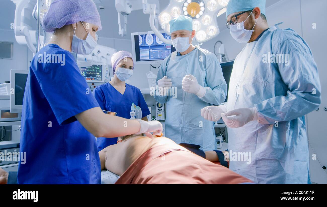 Dans la salle d'opération de l'hôpital, l'anesthésiologiste applique le masque d'anesthésie à un patient, les assistants désinfectent avec l'iode lieu d'incision, les chirurgiens Banque D'Images
