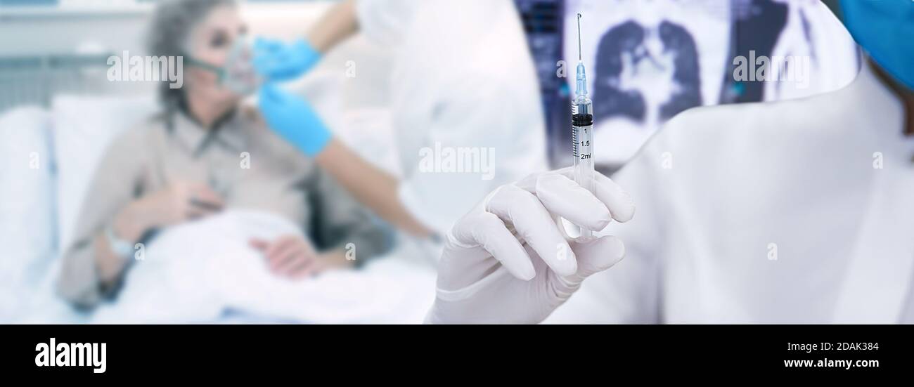 Vaccination du coronavirus.médecin tenant une seringue avec un vaccin, sur un patient atteint de pneumonie sur ventilation pulmonaire artificielle. Banque D'Images