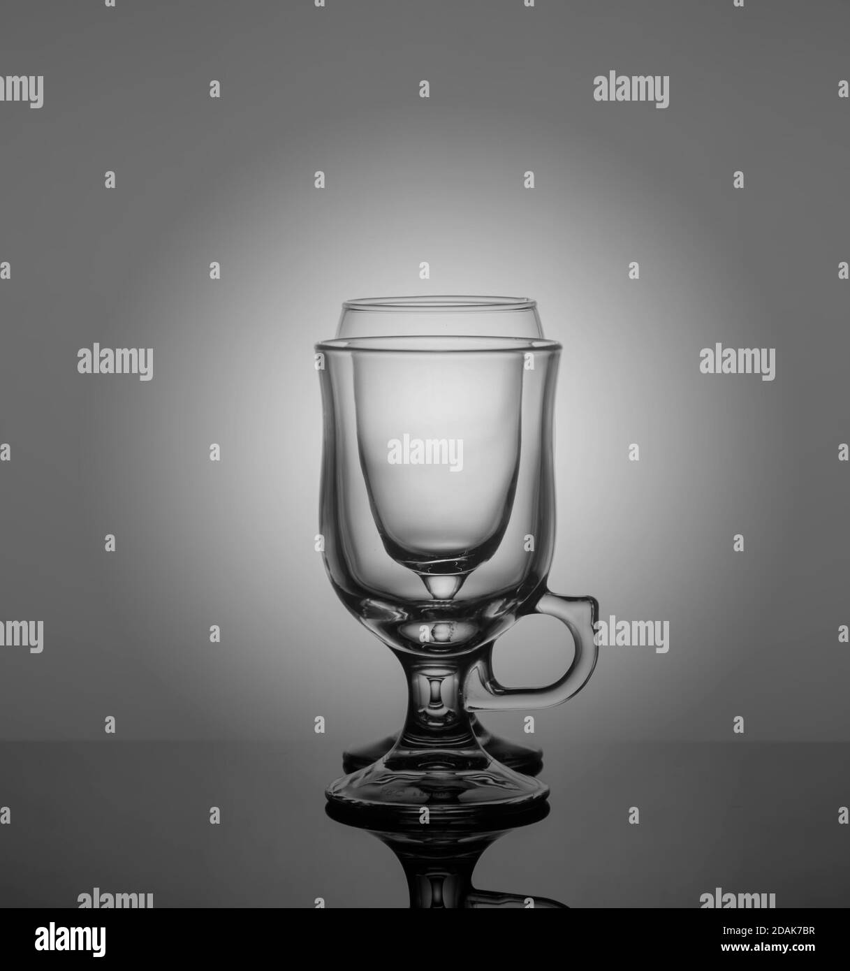 des verres vides sont placés les uns après les autres sur fond sombre avec rétroéclairage Banque D'Images