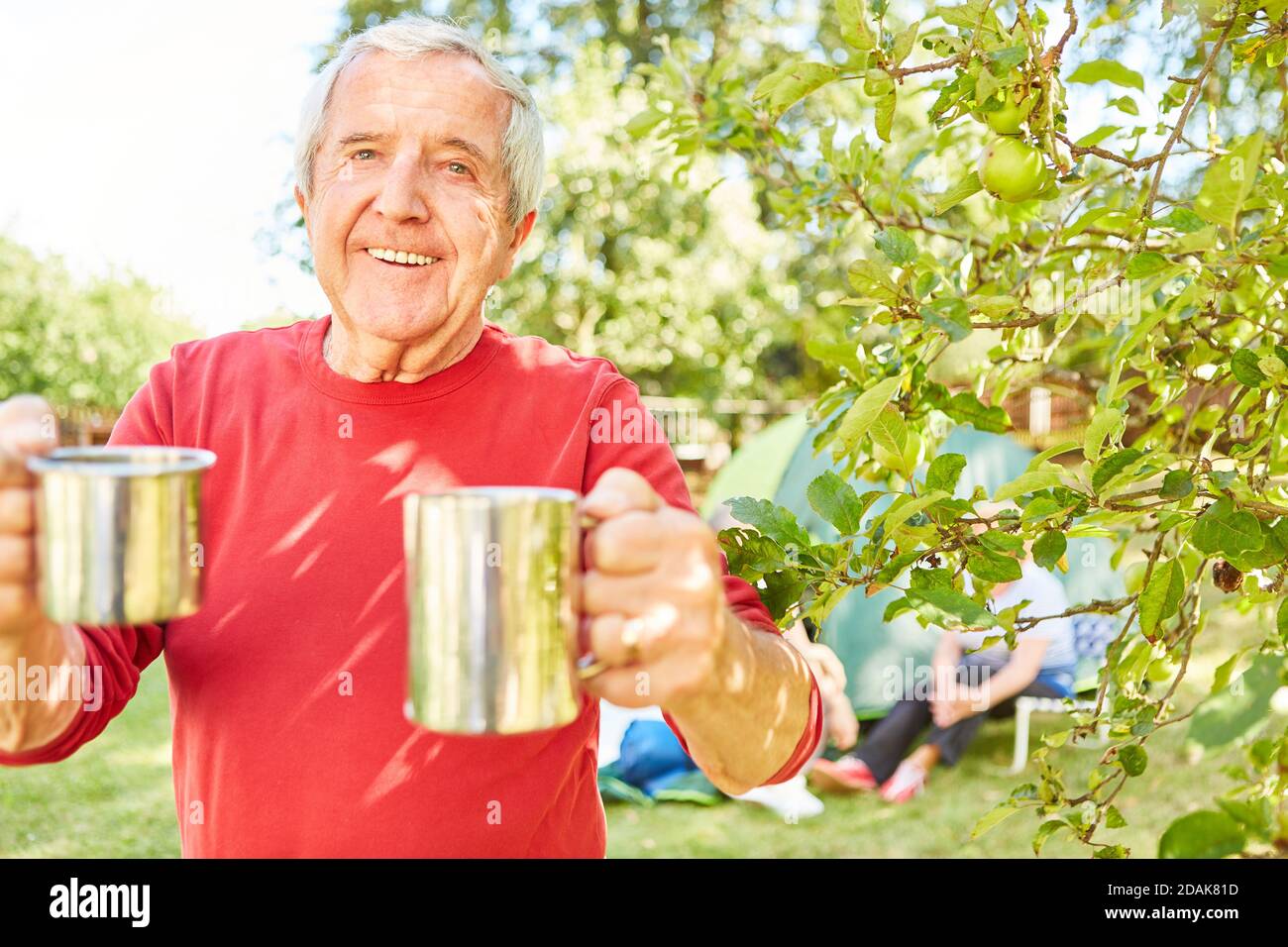 L'homme senior apporte une tasse de café pendant le camping comme un signe d'hospitalité Banque D'Images