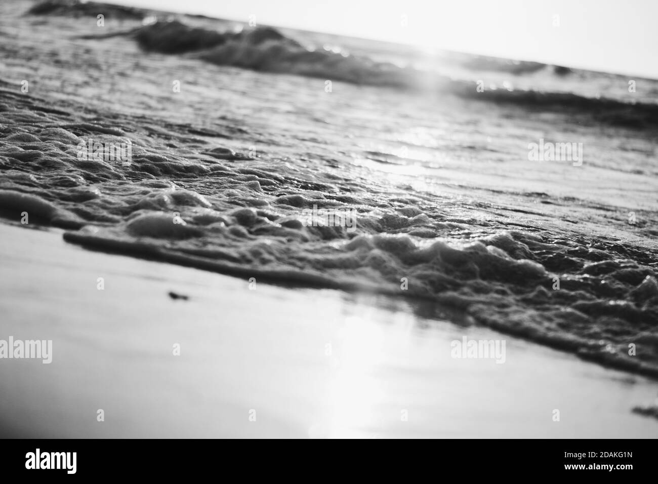 gros plan sur les vagues de la mer avec le soleil juste au-dessus de la horizon au coucher du soleil nostalgique Banque D'Images