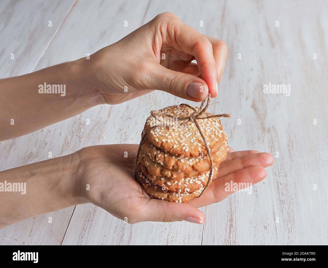 Mains tenant une pile de biscuits de sésame frais. Banque D'Images