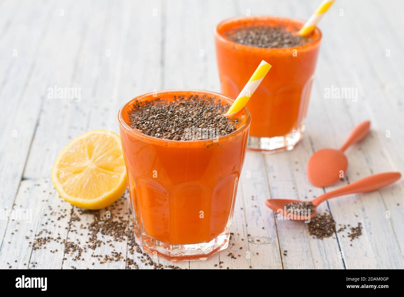 Cocktail de carottes avec des graines de citron et de chia dans des verres sur fond bleu clair, foyer sélectif. Boisson saine et délicieuse Banque D'Images