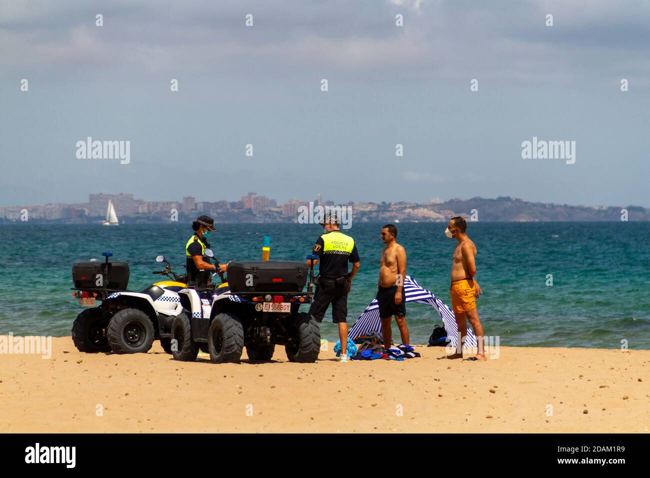Alicante, ESPAGNE - août 8 2020 deux policiers locaux qui patrouillent sur la plage d'Urbanova sur un quad, emprisonnent deux personnes soupçonnées de voler les biens Banque D'Images