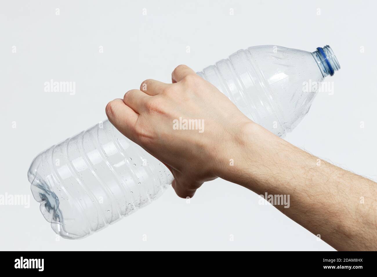 Main tenant une bouteille en plastique vide isolée sur fond blanc Banque D'Images