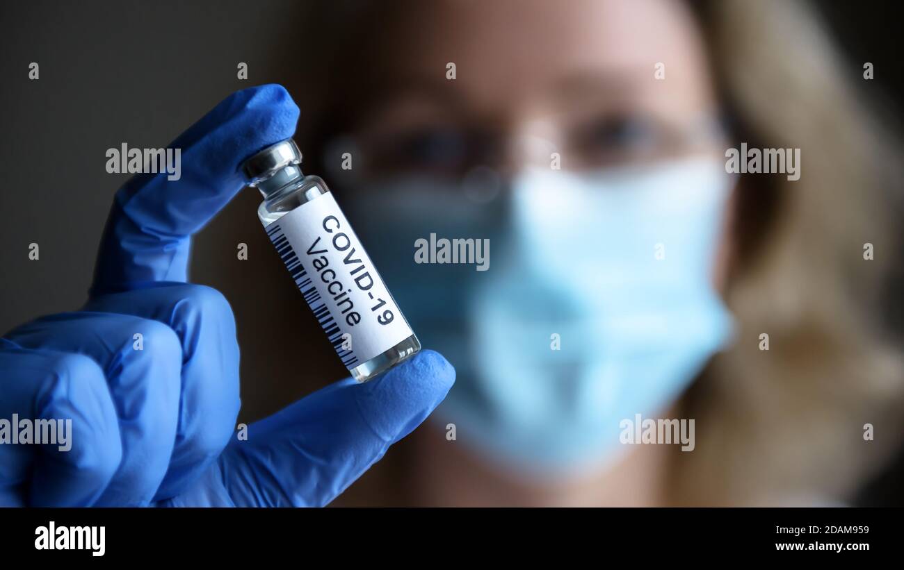 Le vaccin COVID-19 en gros plan, une femme médecin et une bouteille avec un médicament pour la guérison du coronavirus en laboratoire. Concept de traitement du virus corona Banque D'Images