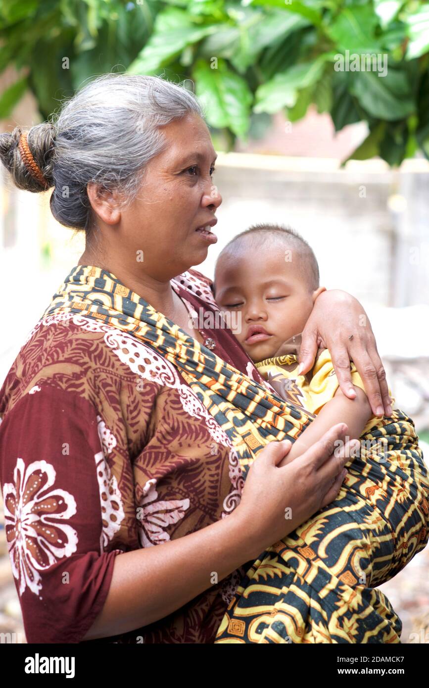 Femme indonésienne tenant bébé dans un tissu de transport. Pringgasela, Lombok, Indonésie Banque D'Images