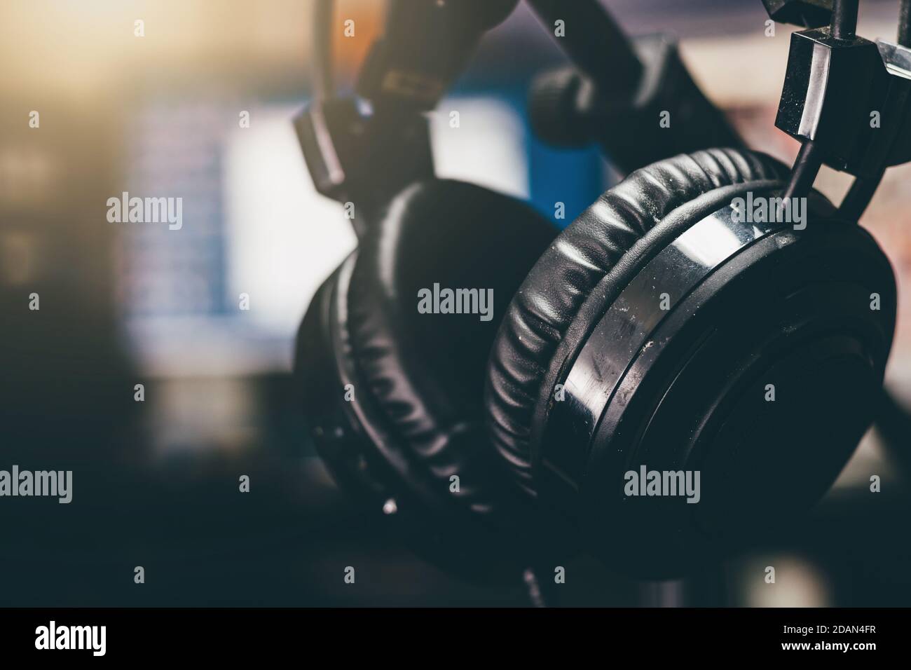 Casque d'écoute noir utilisé sur un support dans un studio. Mise au point sélective, arrière-plan flou, gros plan. Banque D'Images