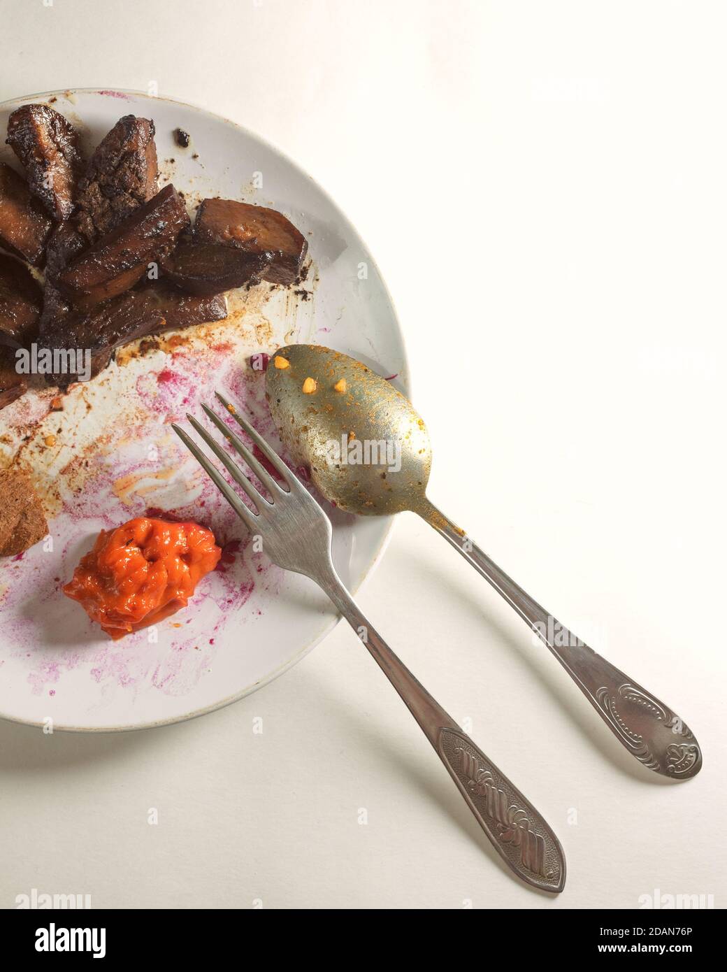 restes de nourriture sur une assiette blanche sale avec couverts un arrière-plan clair Banque D'Images