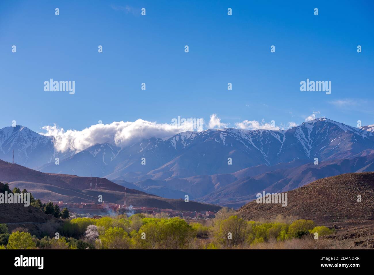 Photo en grand angle de jour d'un magnifique paysage de montagnes enneigées et de buissons et d'un village dans la vallée. Atlas, Maroc. Banque D'Images