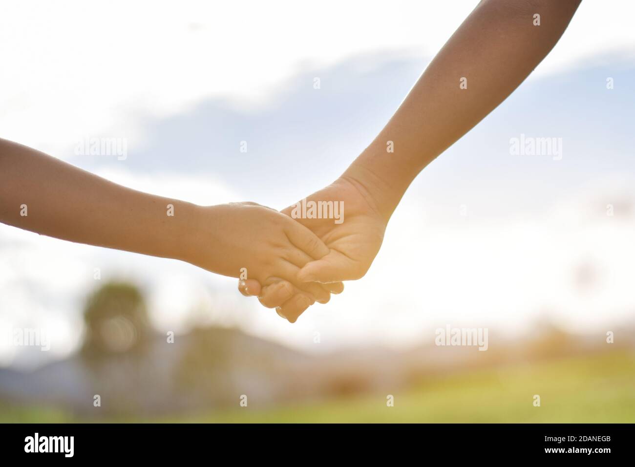 Les mains de deux enfants se tenant les uns les autres sur le terrain. Concept d'assistance mutuelle et d'amitié Banque D'Images