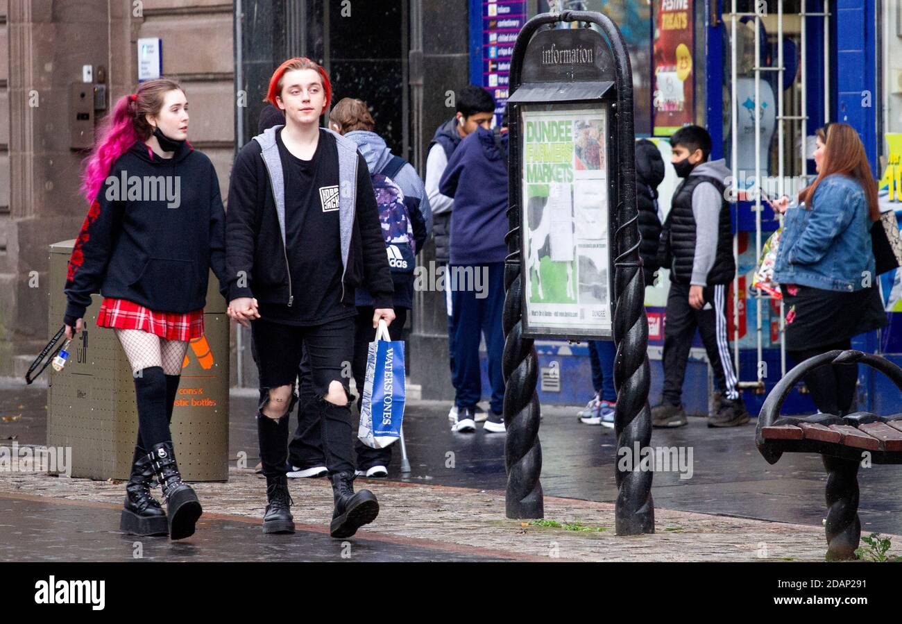 Dundee, Tayside, Écosse, Royaume-Uni. 14 novembre 2020. UK News Covid-19 Lockdown. Les personnes qui marchent dans les rues de Dundee avec peu de magasins de vêtements essentiels ouverts depuis que la restriction plus stricte de niveau 3 Covid-19 Lockdown a été appliquée. Un couple à la mode avec différentes coiffures de couleur sont conscients des directives de distanciation sociale et le port de masques de visage marchant ensemble tenant les mains dans le centre-ville dans un après-midi froid et humide de novembre. Crédit : Dundee Photographics/Alamy Live News Banque D'Images