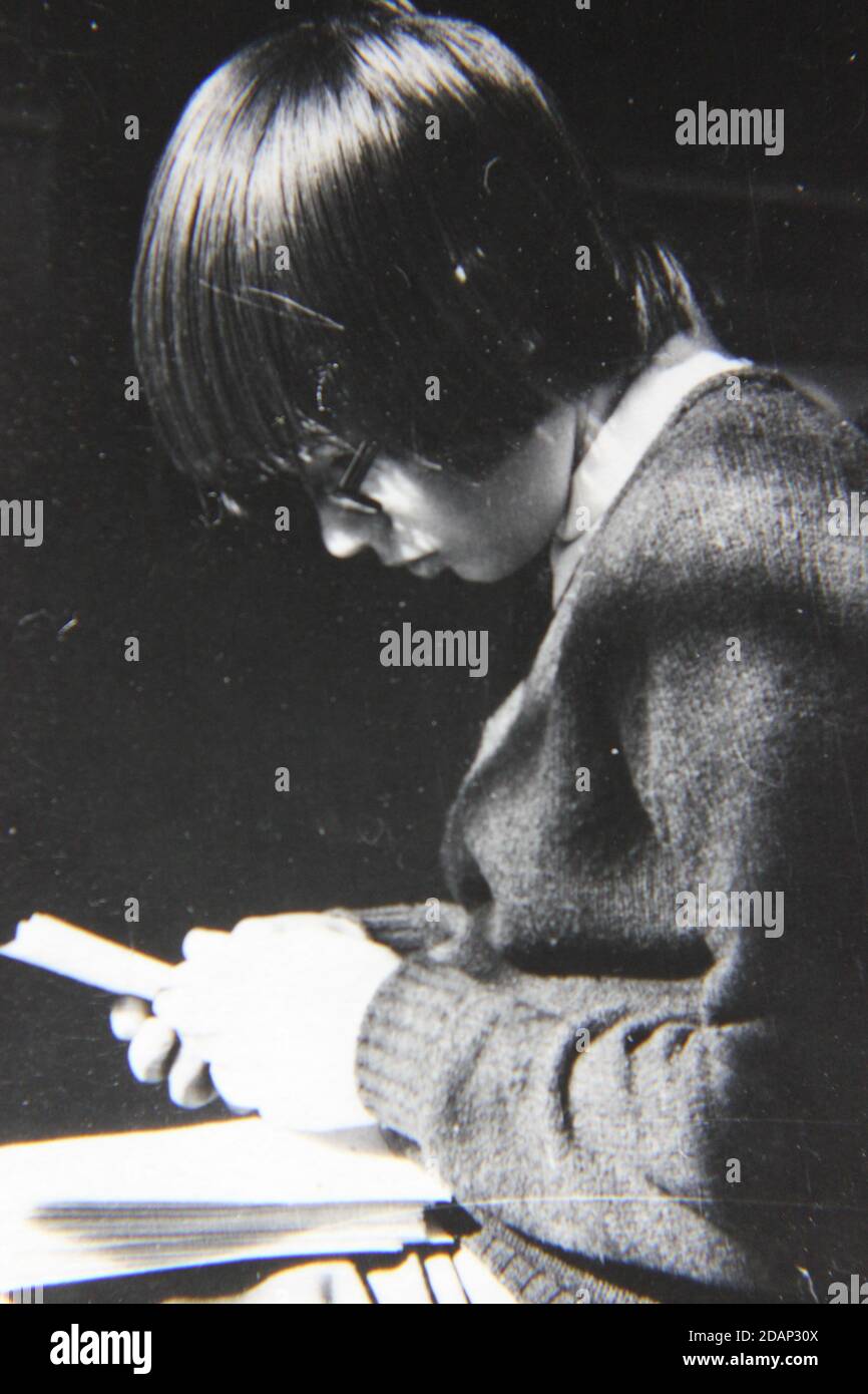 Belle photographie en noir et blanc vintage des années 1970 d'un jeune enfant lisant un livre. Banque D'Images
