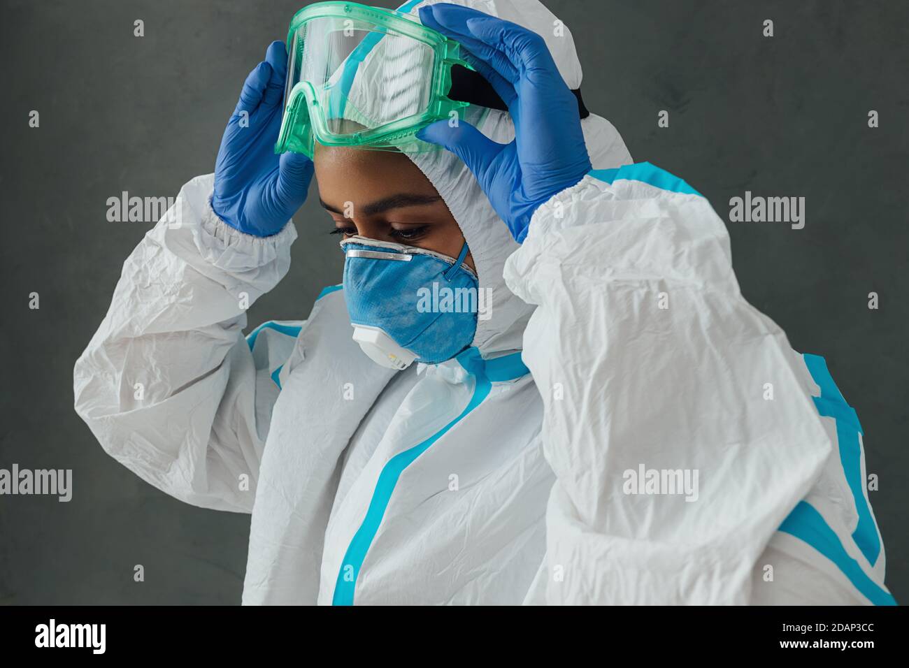 Femme médecin spécialiste mettant des lunettes de protection. Médecin en costume de protection se préparant au travail pendant une pandémie. Banque D'Images