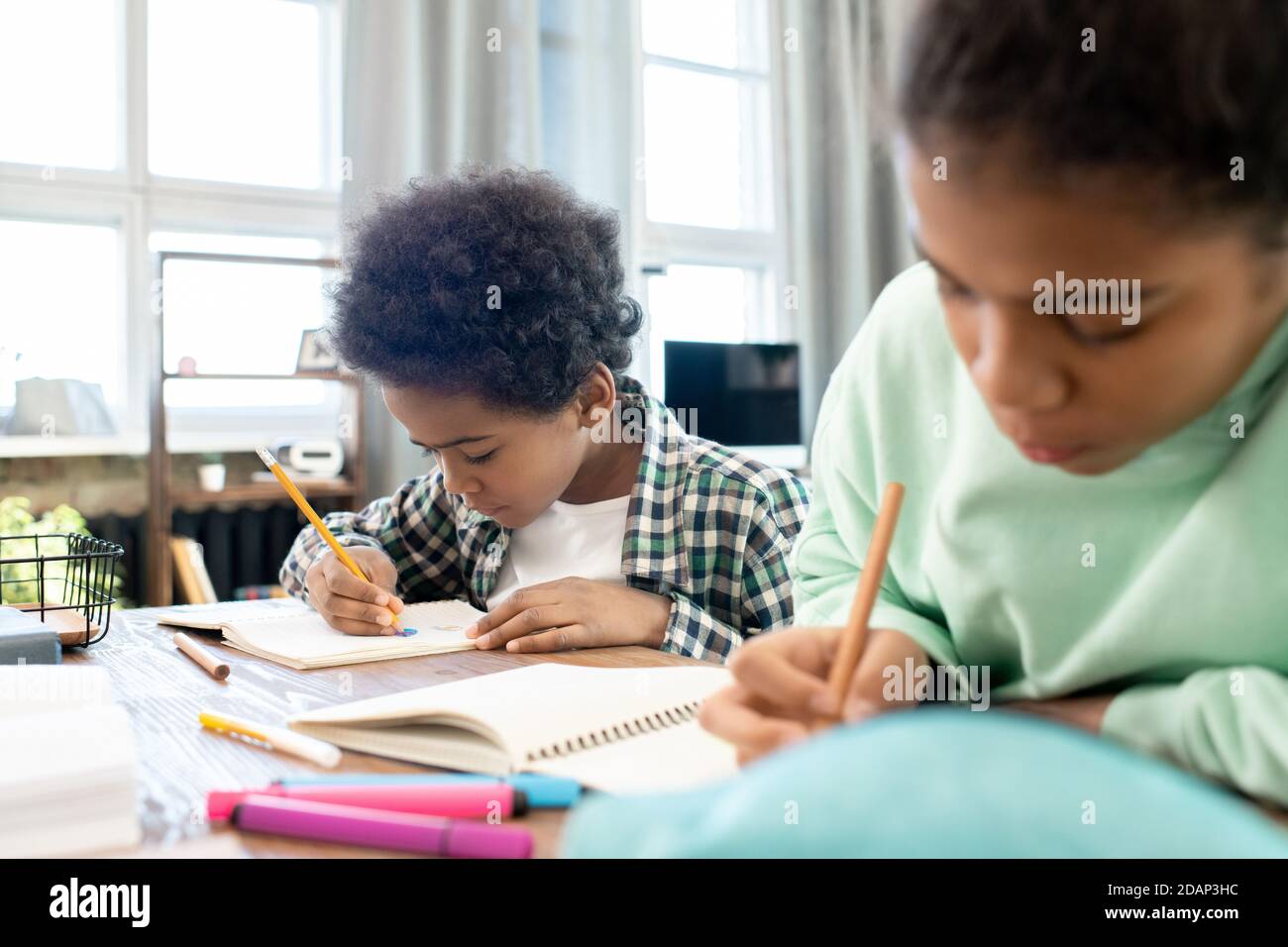 Mignon garçon élémentaire en vêtements décontractés et sa sœur faisant des notes dans les copybooks Banque D'Images