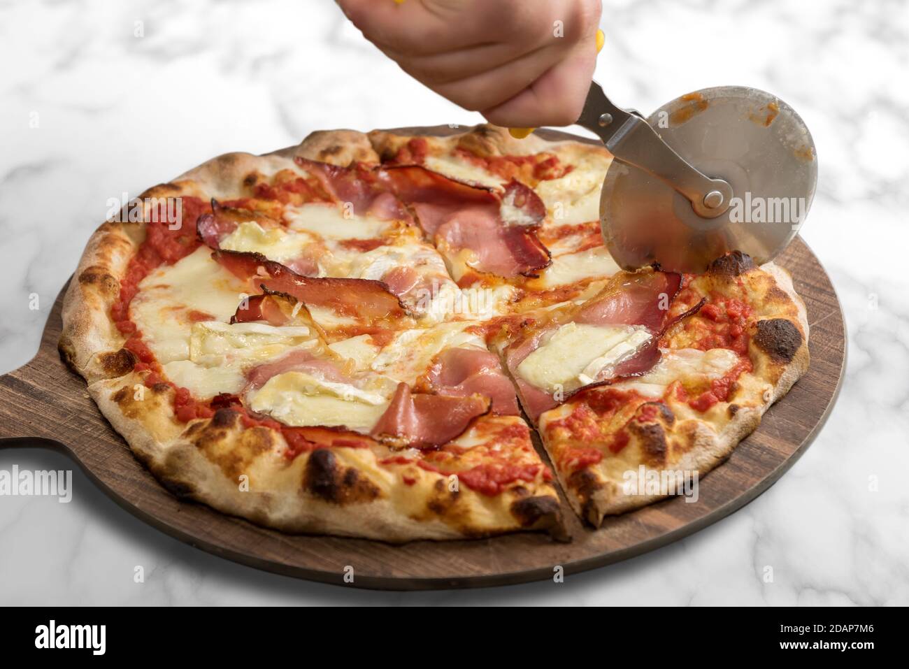 Pizza au bacon ou au fromage blanc et à la brie et à la sauce tomate. Produit italien sur planche à découper en bois avec roue à couteaux sur fond de marbre Banque D'Images
