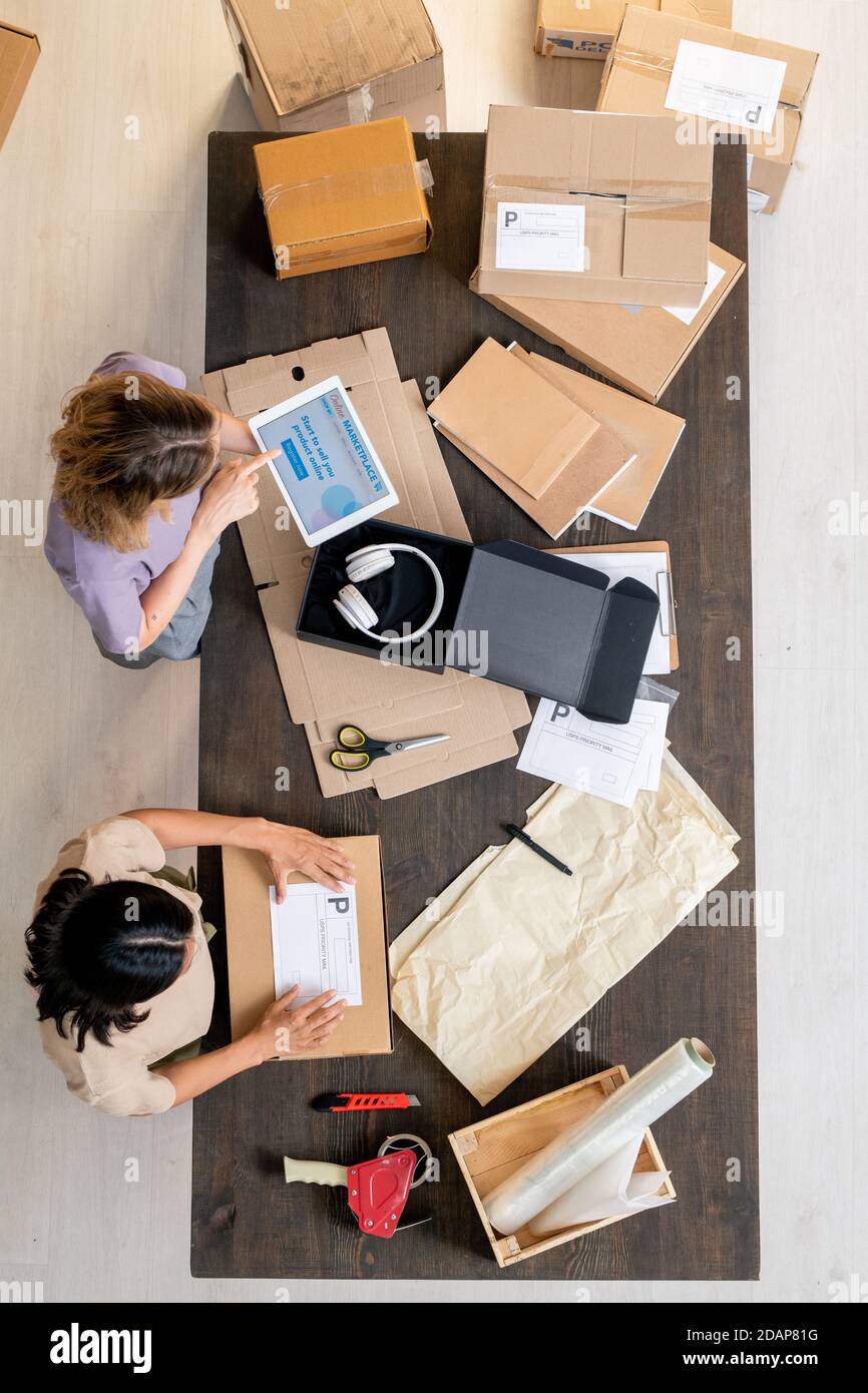 Vue de dessus de deux jeunes femmes managers vérifiant les données en ligne et des commandes d'emballage Banque D'Images