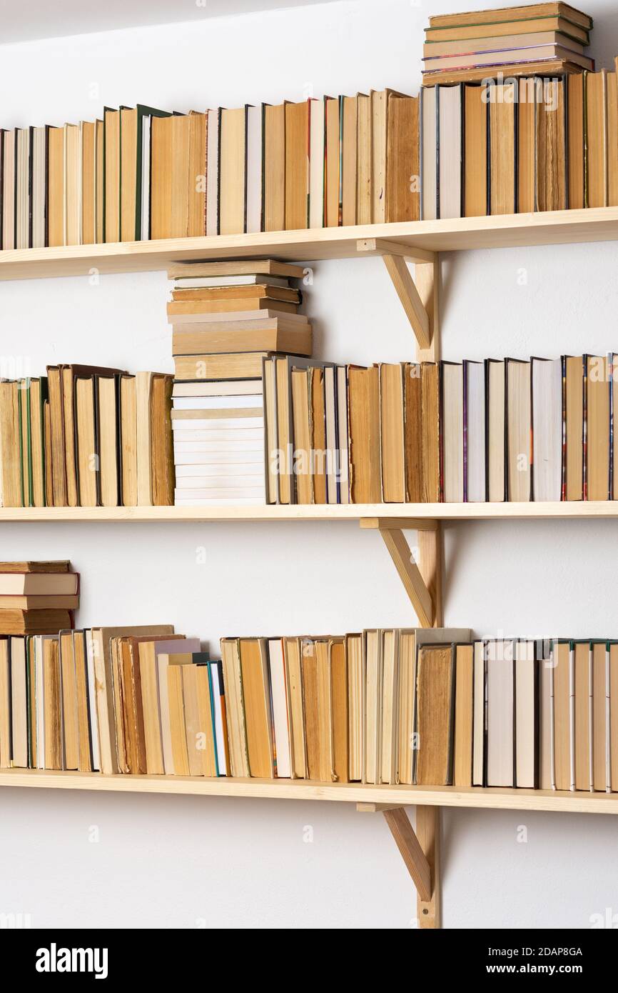 Étagères en bois clair avec livres à dossier rigide rentournés dans un  intérieur blanc, bibliothèque à la maison Photo Stock - Alamy