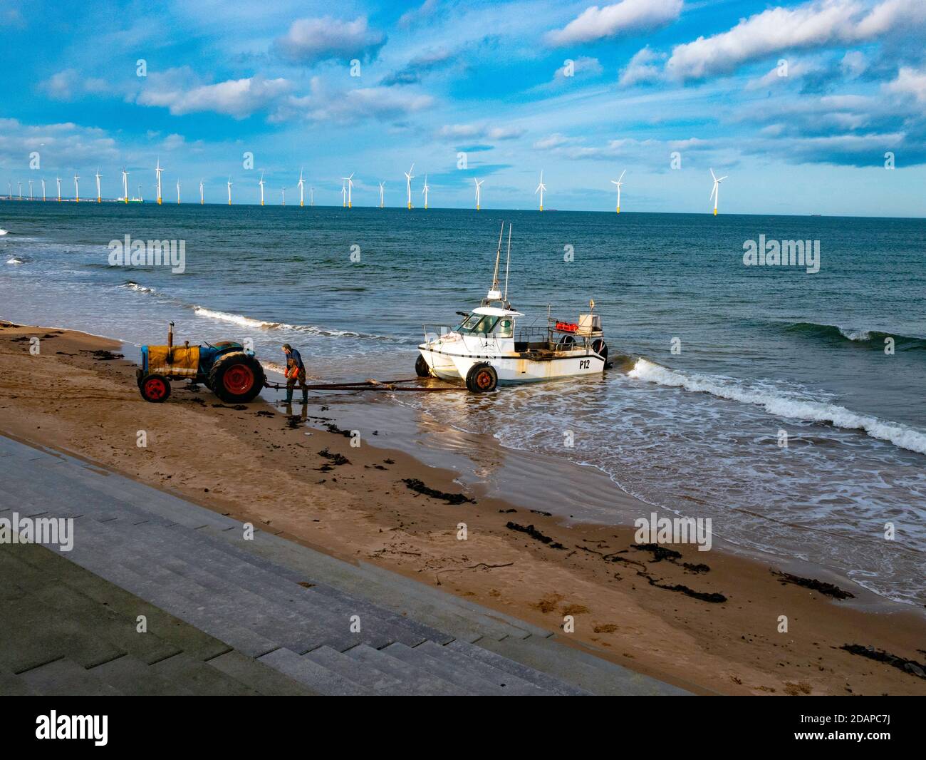 Pêcheur accrochant un tracteur pour transporter son bateau blanc P12 hors de la mer Redcar Cleveland Royaume-Uni Banque D'Images