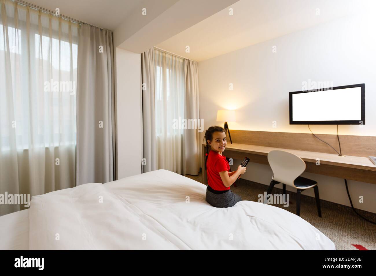 Petite fille enfant avec télécommande regarder la télévision sur le lit