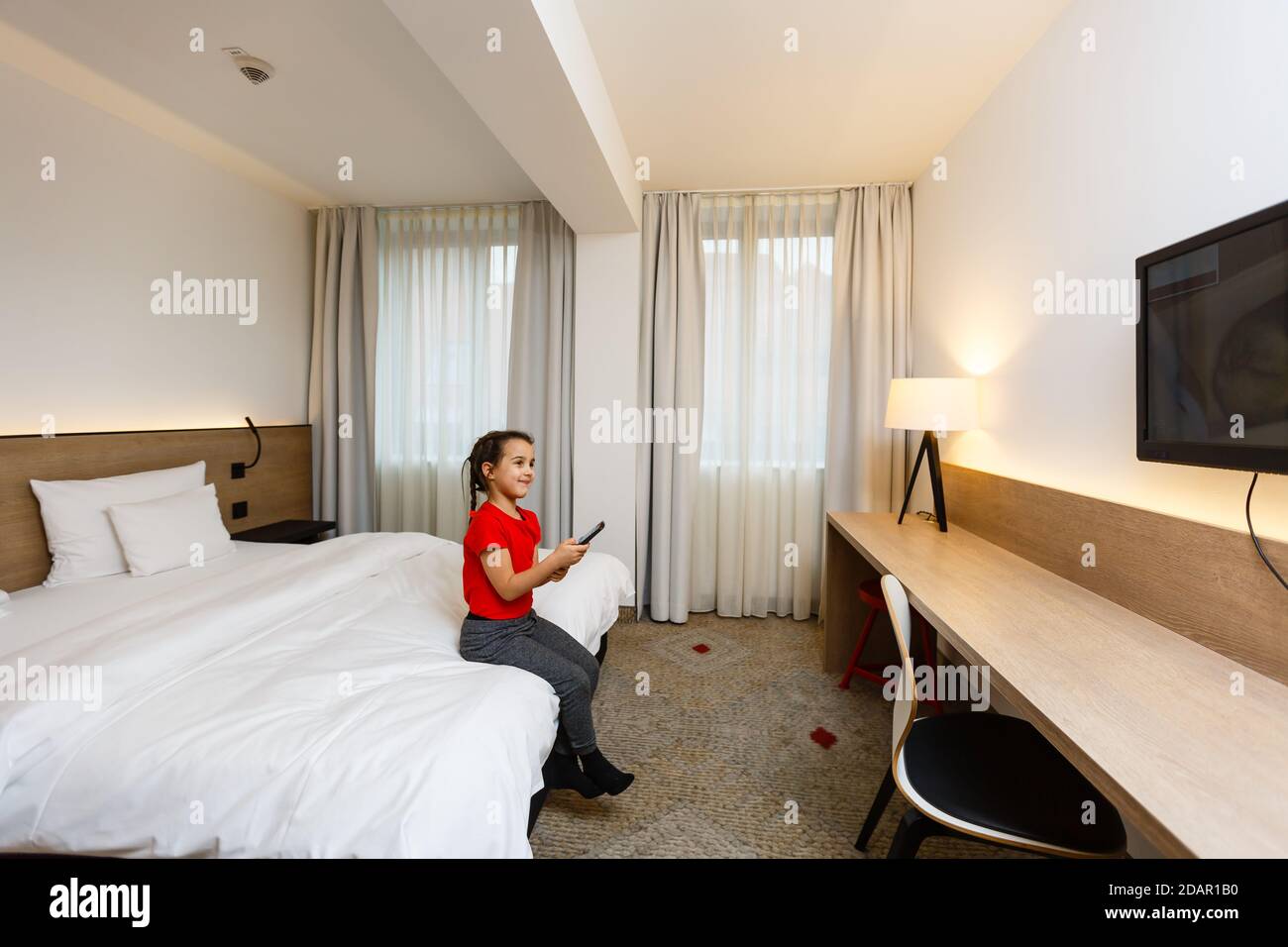 Petite fille enfant avec télécommande regarder la télévision sur le lit